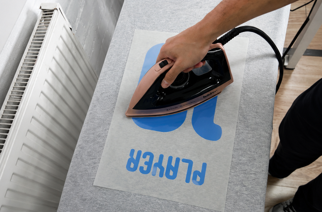 Pressing a hot iron over the protective sheet covering the transfer